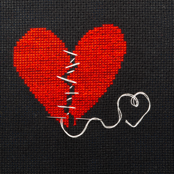 two halves of the heart sewn with white thread, embroidered on black cloth