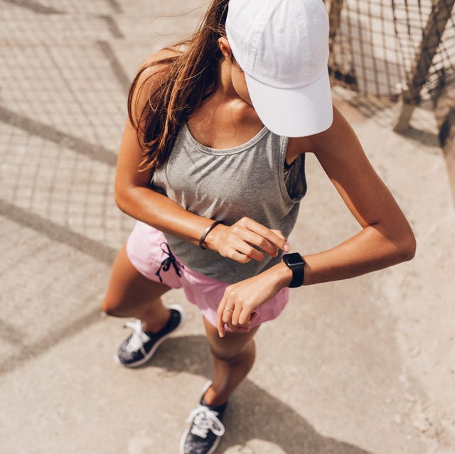 young woman checking progress on smart watch female runner looking at smart watch heart rate monitor