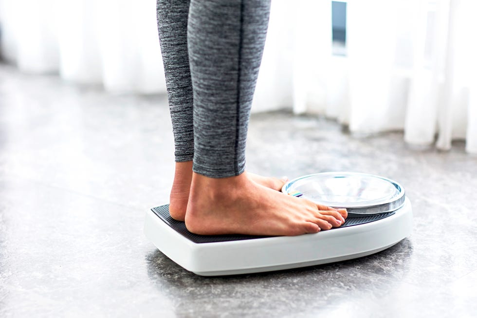 elderly woman standing barefoot on a bathroom scale and measuring