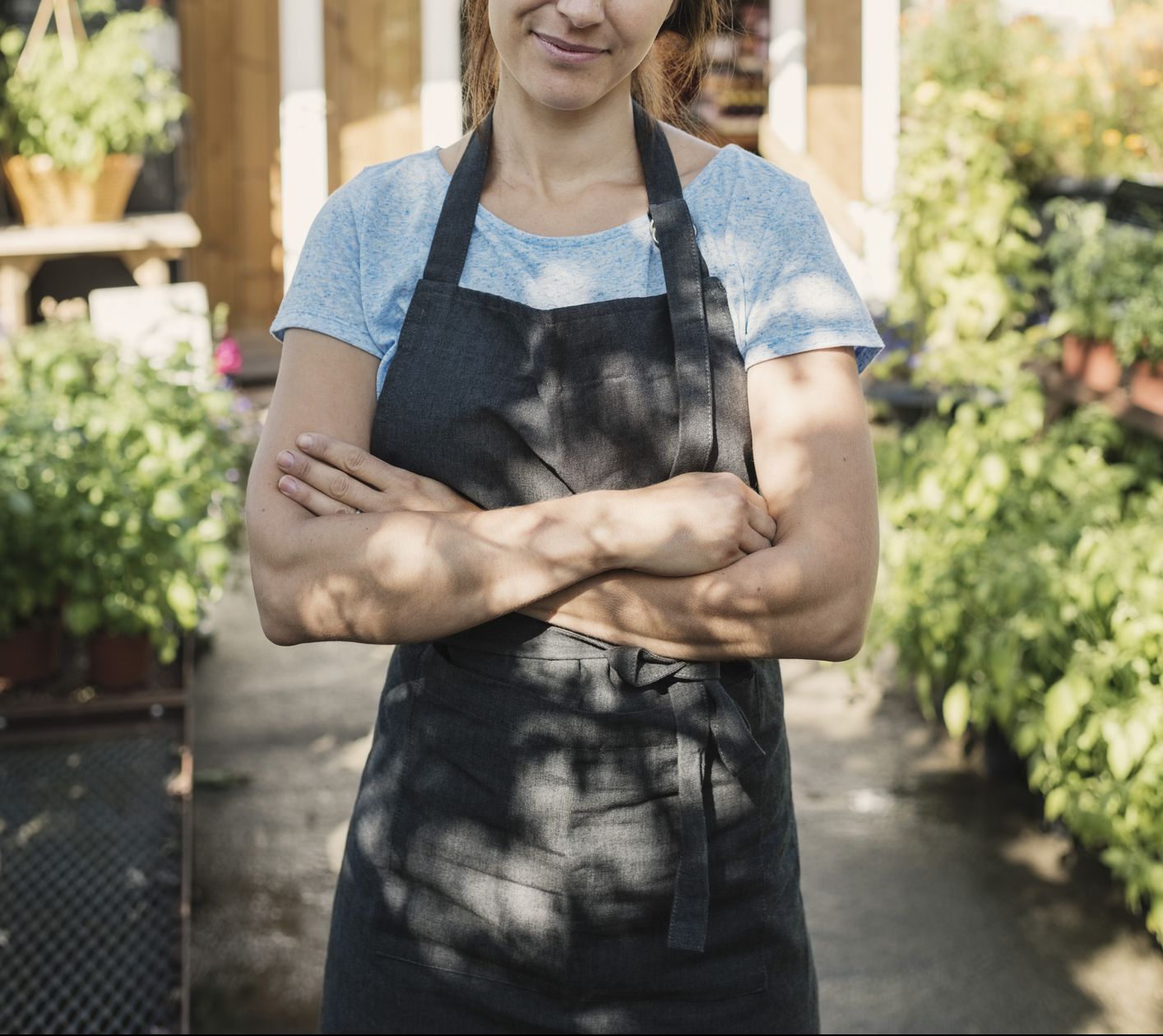 Portrait of confident female owner standing in garden against food store