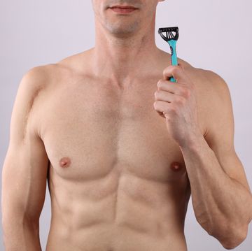 male depilation young attractive muscular man using razor to remove hair from his body