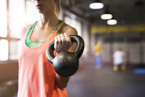 Unrecognizable young fit woman in gym working out, holding kettlebell