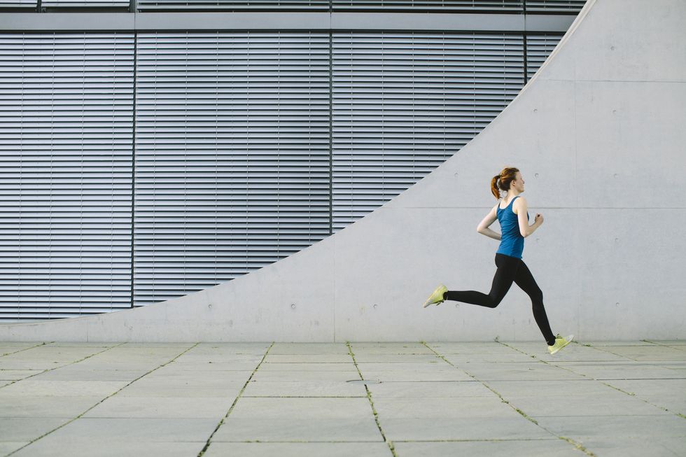 young woman running strides in front of a modern building