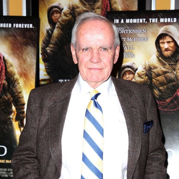 author cormac mccarthy stands at the premier of the road in front of film posters