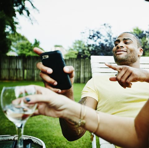 smiling man hanging out with friends in backyard on summer evening