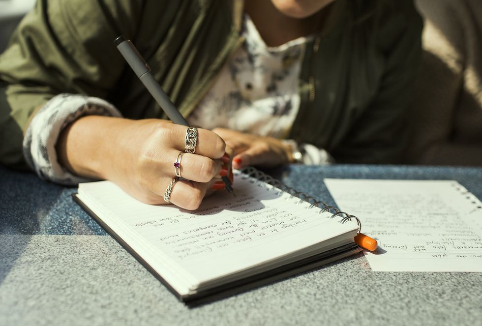 midsection of woman writing on diary in train