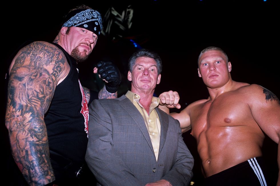 Vince McMahon (C) flanked by WWE superstars The Undertaker (L) and Brock Lesnar (R)