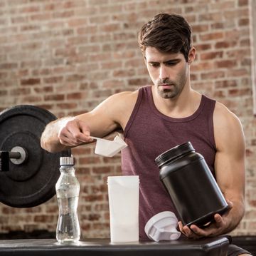 man adding supplement from tin to bottle at the gym