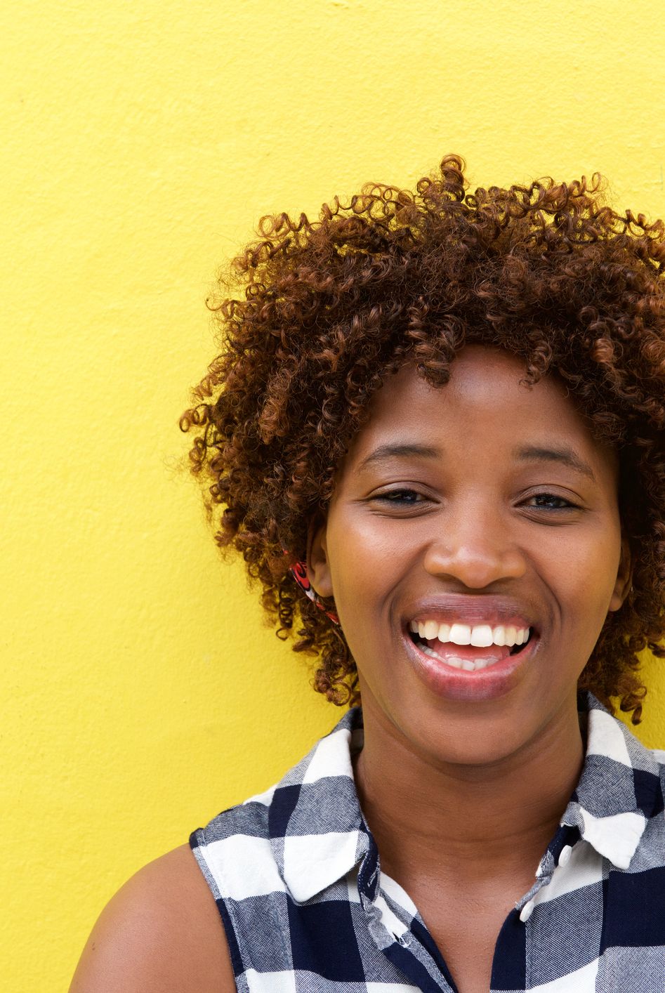 african lady laughing against yellow wall