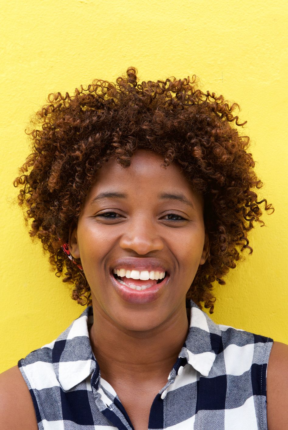 african lady laughing against yellow wall