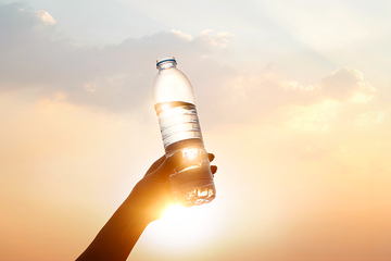 hand holding drinking water on sunset background