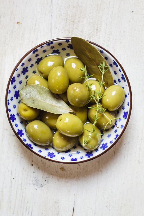 green olives in bowl with thyme and bay leaf