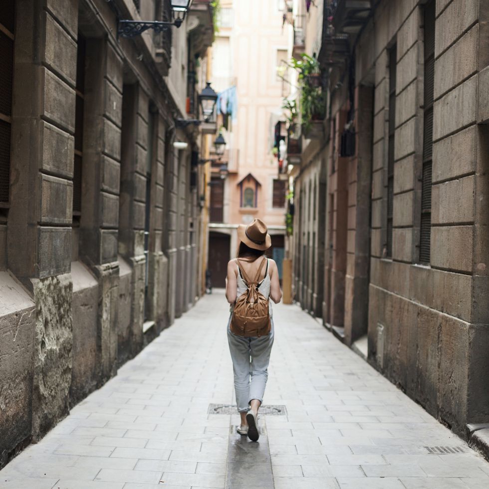 Una mujer camina por una calle estrecha de Barcelona
