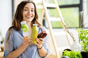 beautiful happy woman sitting with drinks and healthy green food at home vegan meal and detox concept