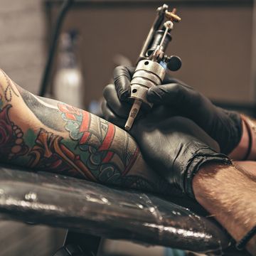 close up tattoo machine man creating picture on hand with it in salon