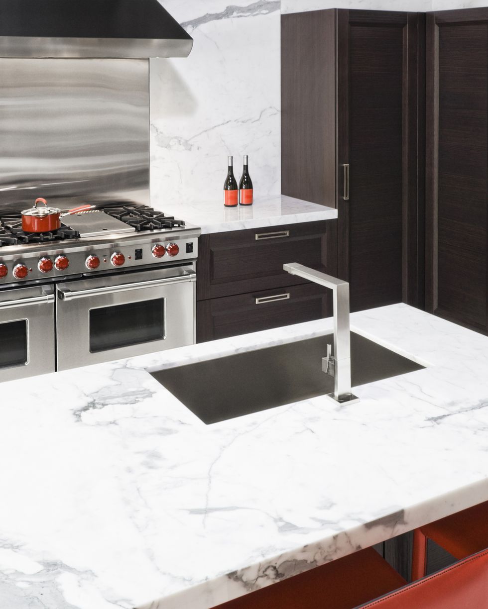 Una hermosa cocina con un diseño en blanco y mármol, un piso de mármol, una  puerta de horno abierta y un estante extraíble.