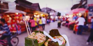 Cropped Image Of Person Holding Street Food In Market At Dusk