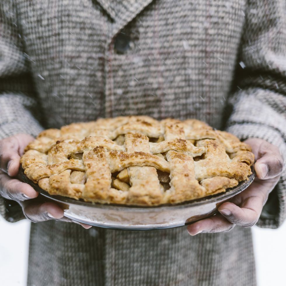 a man is photographed as he is holding an apple pie while it is snowing outside