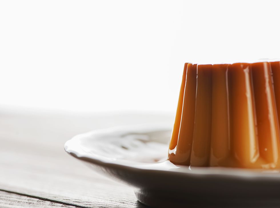 Flan on white plate with brightly lit background.