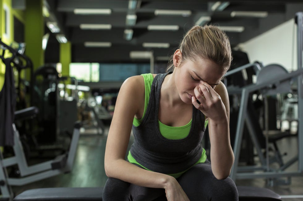 young woman having headache after working out in a health club