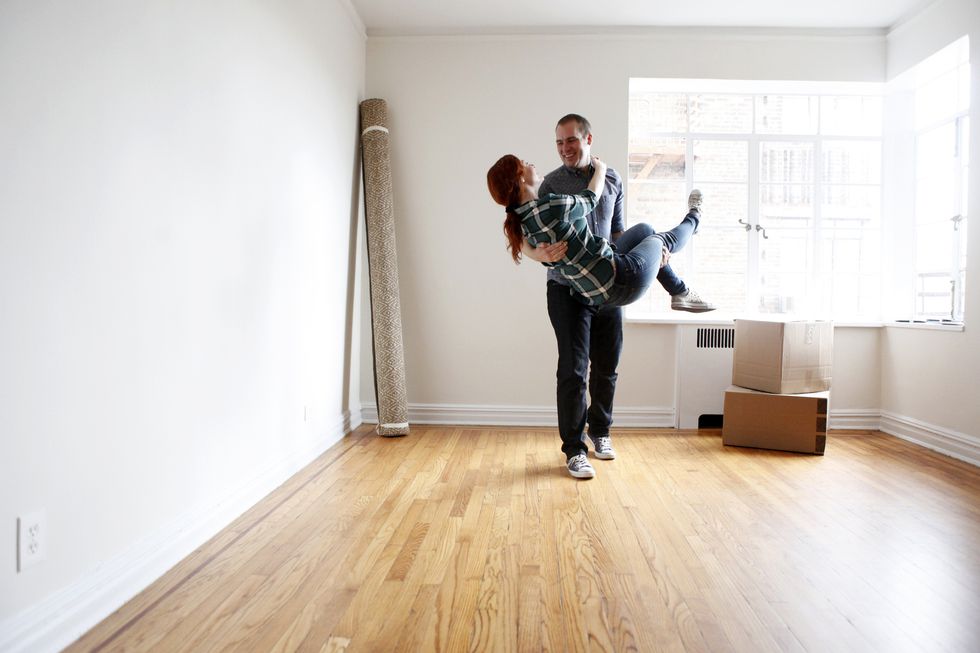 man lifting woman in empty apartment