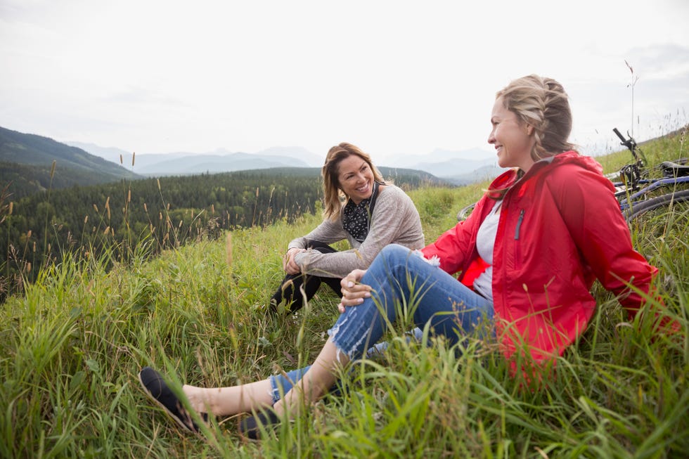 Female friends relaxing in grass in remote rural field