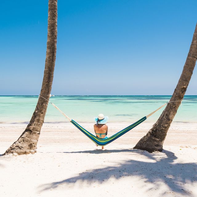juanillo beach playa juanillo, punta cana, dominican republic woman relaxing on a hammock on a palm fringed beach