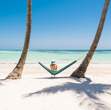 juanillo beach playa juanillo, punta cana, dominican republic woman relaxing on a hammock on a palm fringed beach