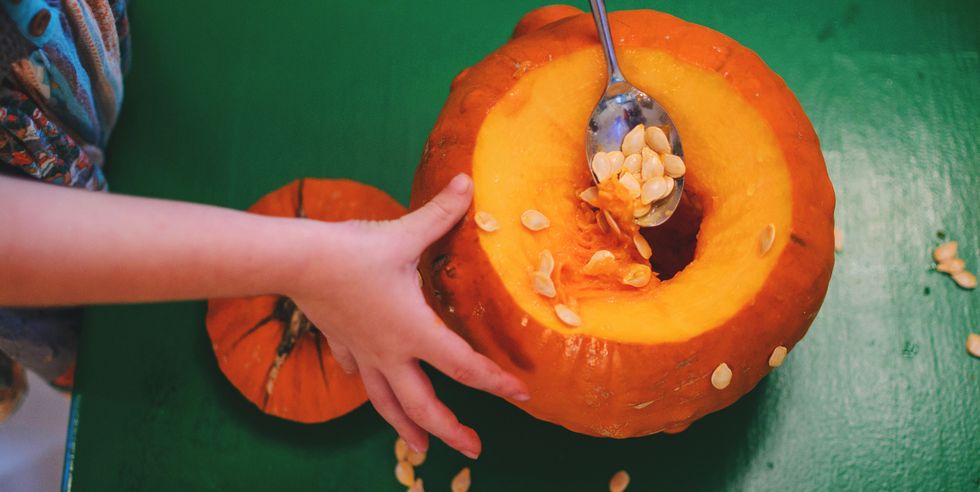 girl removing seeds from a pumpkin