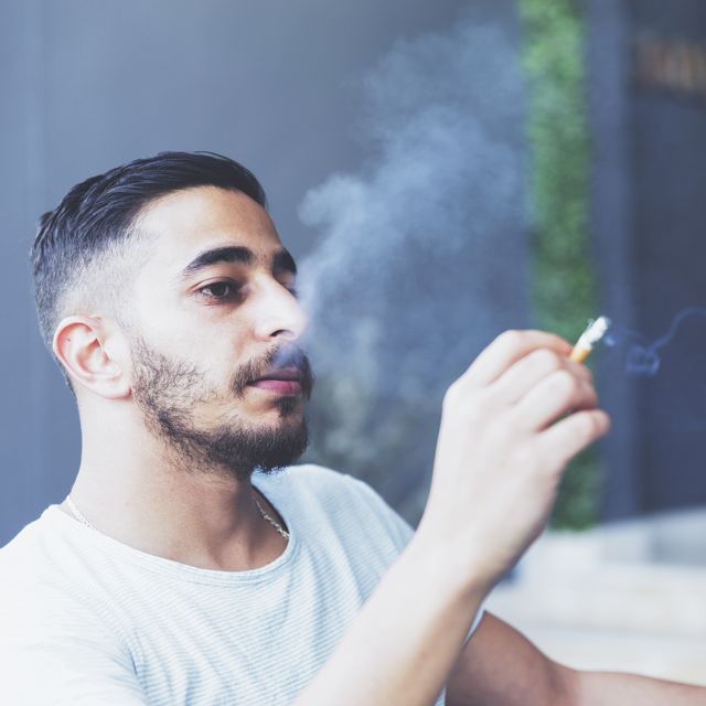 young adult smoking outside at an open cafe