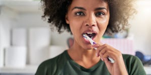 shot of a young woman brushing her teeth in her bathroom