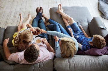 a family at home view from above of two adults and two children seated on a sofa together