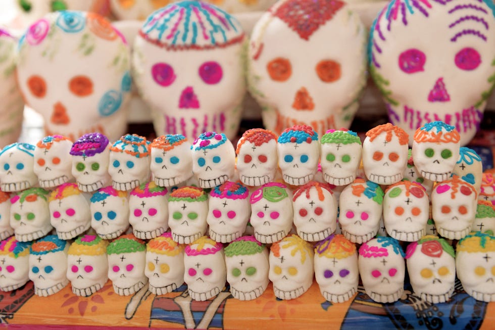 display of several rows of traditional mexican white sugar skulls decorated in various colors on sale for day of the dead celebration