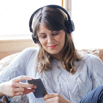 young woman listening to headphones and looking at a smartphone