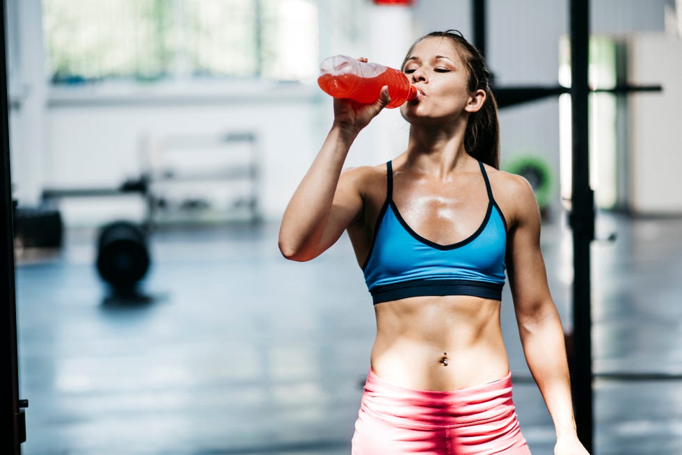 pretty girl drinks flavored water in gym