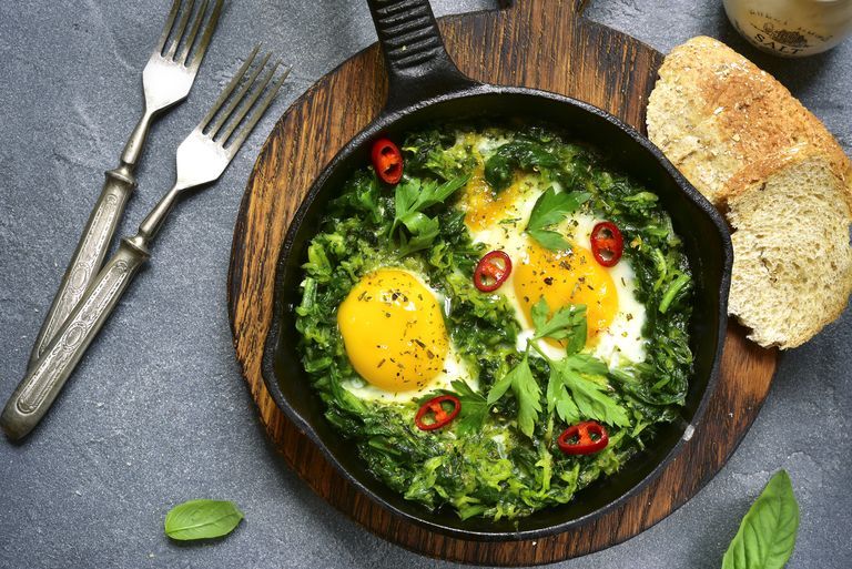 weight loss breakfast green shakshuka in a cast iron pan on a grey slate,stone or concrete backgroundtop view