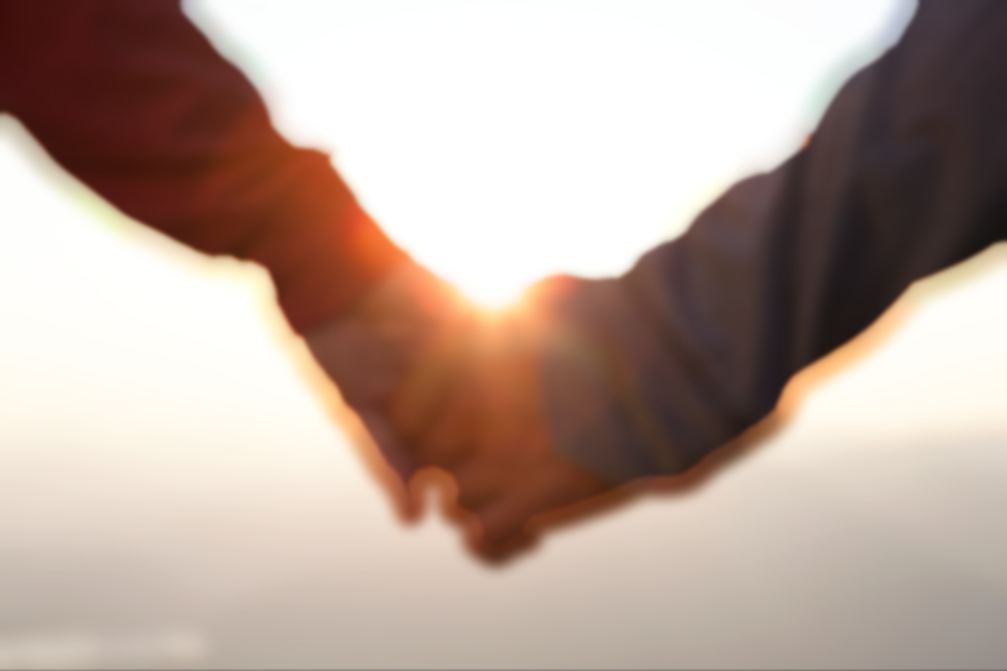 blurred image of two hands holding on a beach