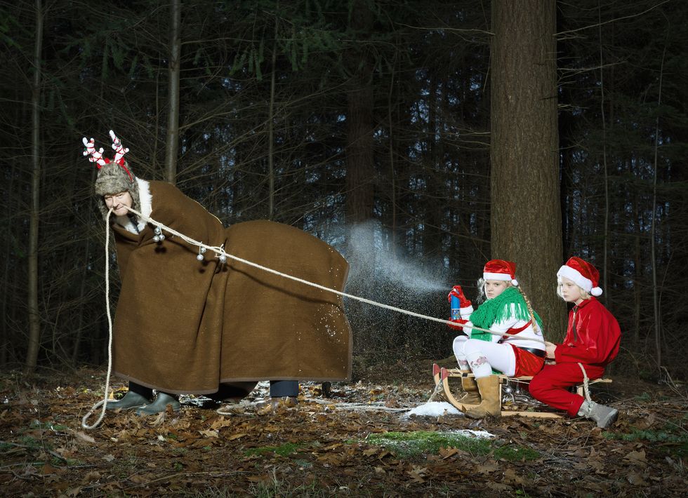 father disguised as reindeer pulling sleigh with children in santa costume
