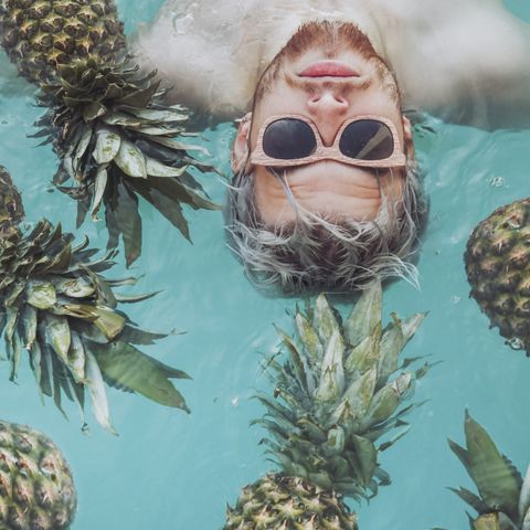 man swimming with pineapples