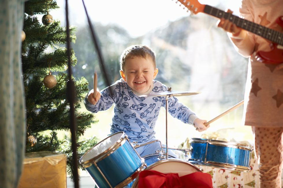 boy and sister playing toy drum kit and guitar on christmas day