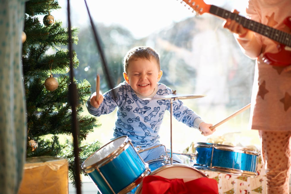 Niño y hermana tocando batería de juguete y guitarra el día de Navidad
