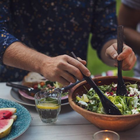 midsection of man mixing salad at table during garden party mens health weight loss tips