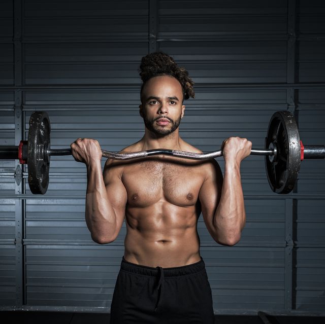 mixed race man lifting weights in gymnasium