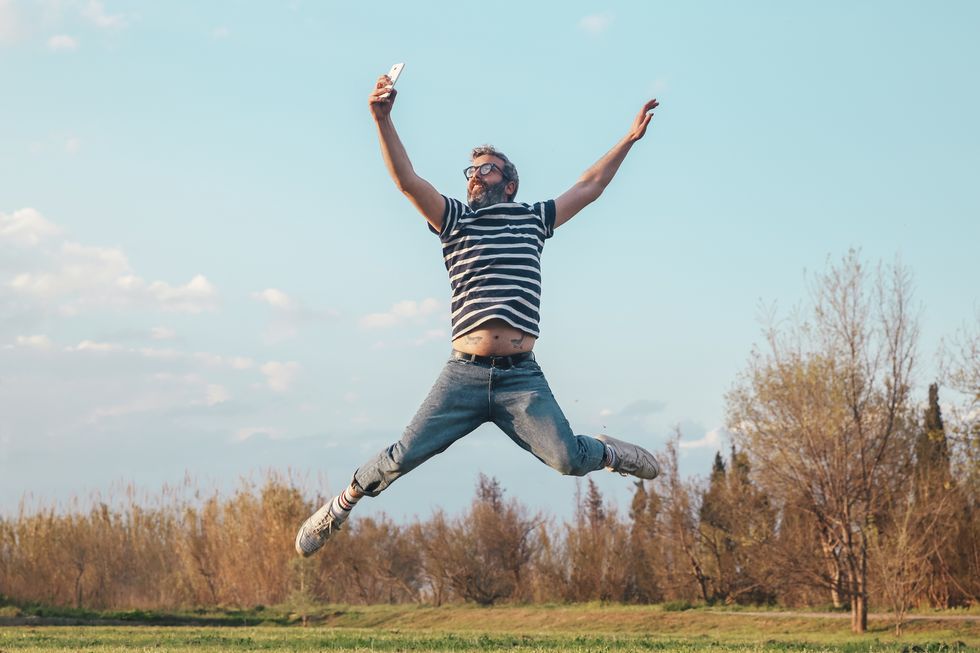 Man jumping in the air while taking photo with smartphone