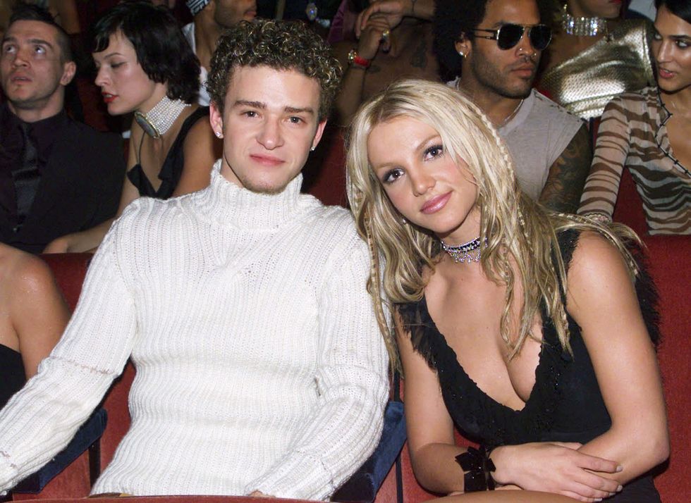 britney spears and justin timberlake in the audience at the 2000 mtv music video awards, with justin wearing a tight white turtleneck sweater and britney wearing a black camisole