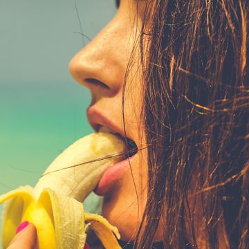 Close-Up Of Woman Eating Banana At Beach