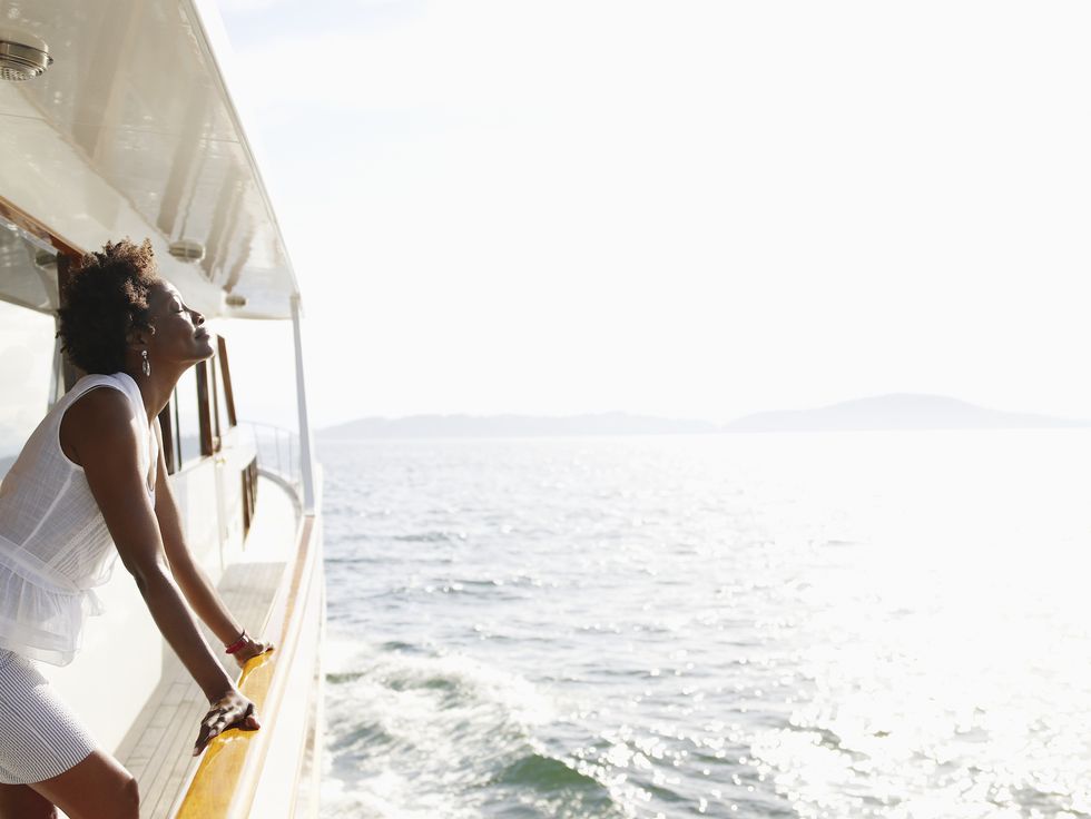  woman leaning against railing on yacht - travelling alone 