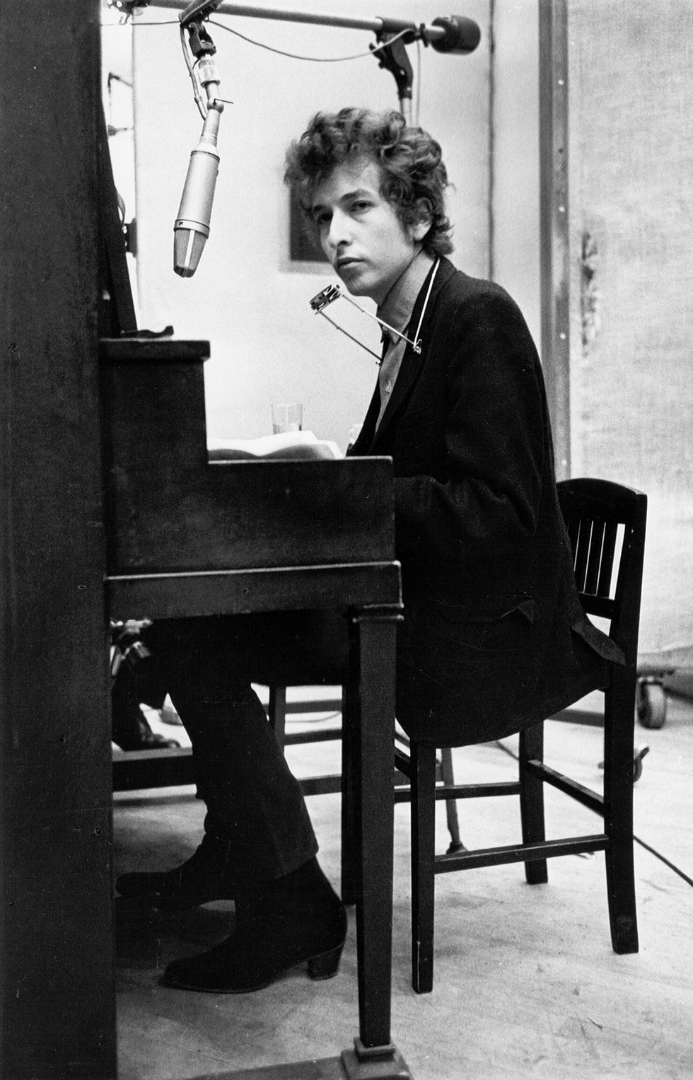 Bob Dylan plays piano with a harmonica around his neck while recording his album 'Highway 61 Revisited' on January 13-15, 1965, in Columbia's Studio A in New York City