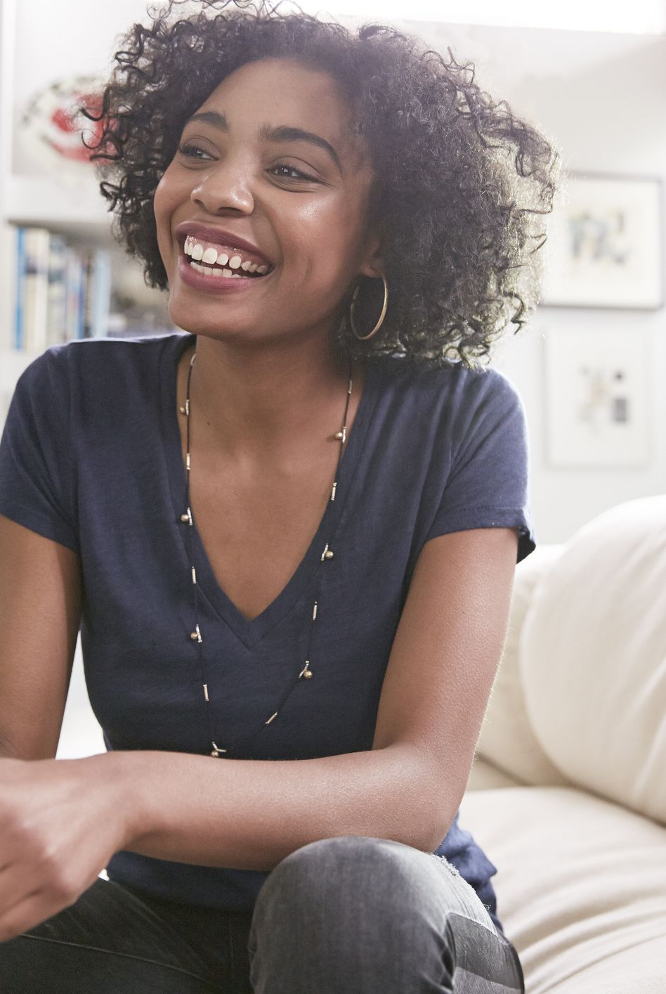 Smiling African American woman with cell phone on living room sofa