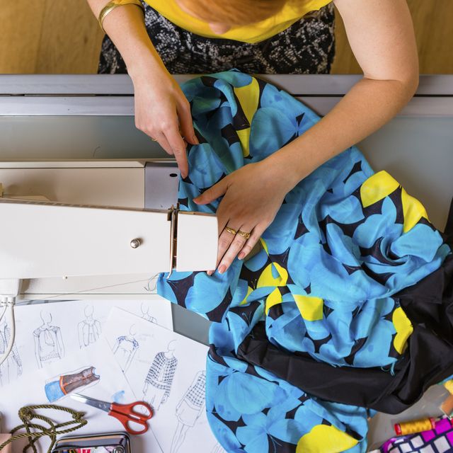 Fashion designer working with sewing machine, top view